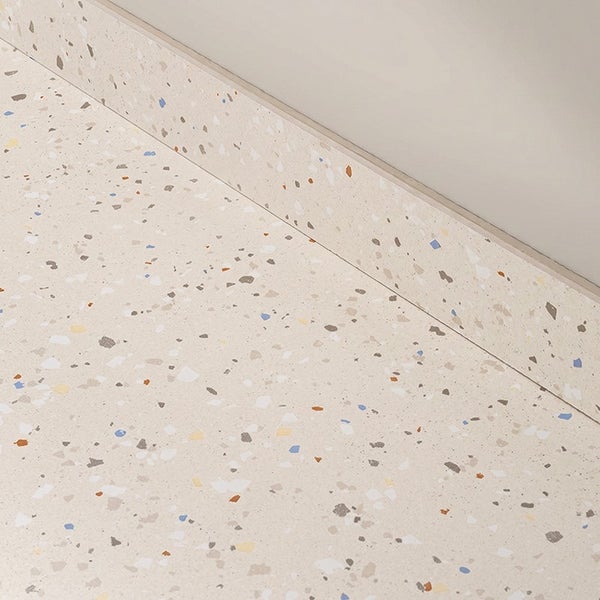 Bodenfliese mit Terrazzo Optik inklusive passender Sockelleiste als Übergang zur Wand