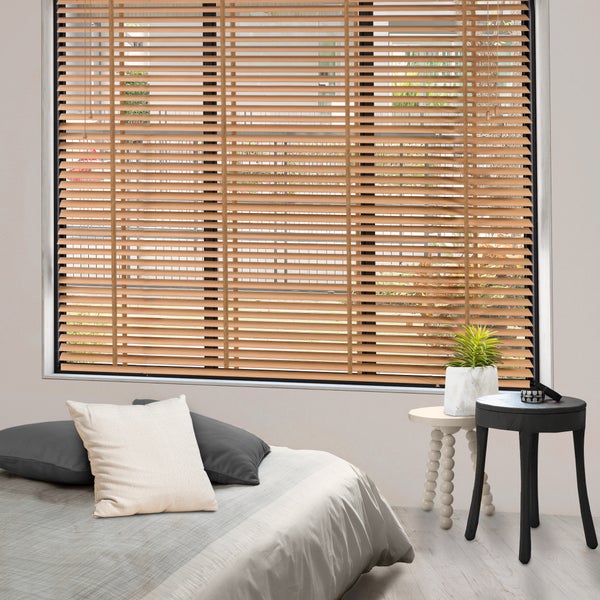 Holzjalousie am Fenster eines Schlafzimmers mit Bett und Beistelltischen