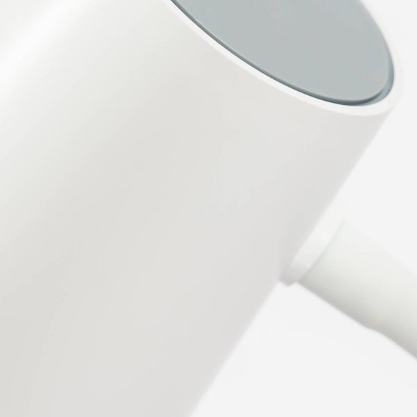 Detailansicht eines weißen elektrischen Wasserkochers mit grauem Deckel und weißem Griffansatz.