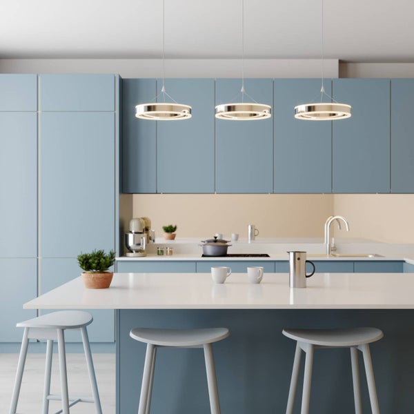 Drei moderne LED-Ring-Pendelleuchten hängen über einer weißen Kücheninsel mit Barhockern in einer hellen, organisierten Küche.