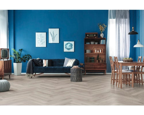 Wohnzimmer mit Sofa, Tisch und Regalen vor einer blauen Wand