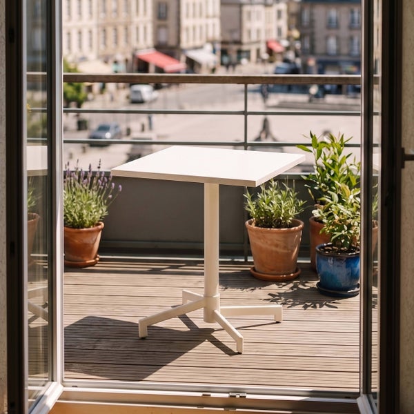 Quadratischer Bistrotisch auf einem hellen Balkon mit Holzboden und Topfpflanzen, moderner Außentisch für Garten und Terrasse.