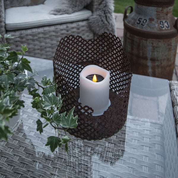 Dekorative LED Kerze in Metallkorb auf einem Tisch im Außenbereich