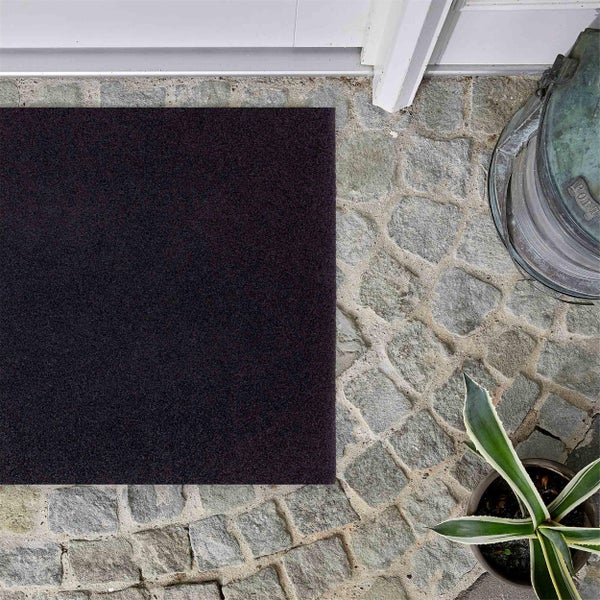 Schmutzfangmatte vor einer Haustür auf Pflastersteinen