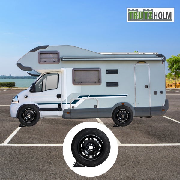 Wohnmobil mit Reifensatz und Auffahrkeilen auf einem Parkplatz. TrutzHolm Logo.