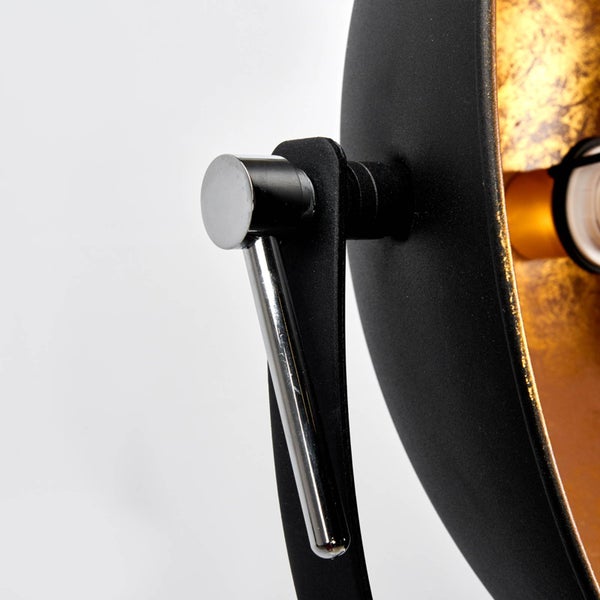 Detailaufnahme einer schwarzen Stehlampe mit verstellbarem Chromgriff und goldfarbenem Reflektor