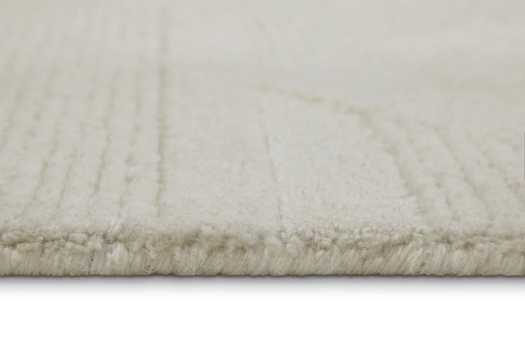 Detailansicht eines hellen Teppichs mit geometrischem Hoch-Tief-Reliefmuster.