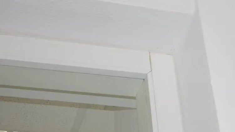 Nahaufnahme einer Gehrungsverbindung an einer weißen Türzarge mit einem sichtbaren Spalt.