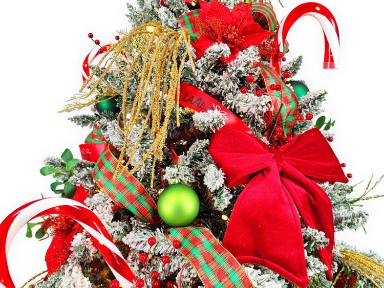 Geschmückter Weihnachtsbaum mit künstlich beschneiten Zweigen, dekoriert mit Kugeln, Schleifen, Zuckerstangen und Blumen als Weihnachtsdeko.