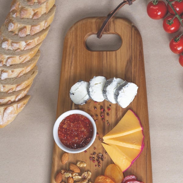 Holzschneidebrett mit Brot, Käse, Marmelade, Nüssen und Kirschtomaten