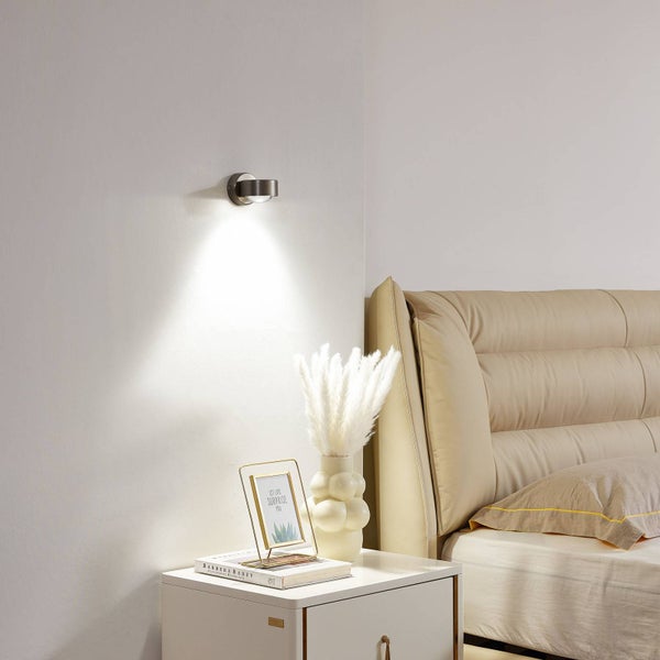 Wandleuchte neben einem Nachttisch mit Dekoration in einem Schlafzimmer.
