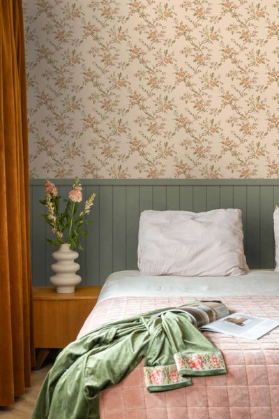 Schlafzimmer mit floraler Tapete und grünem Wandpaneel, kombiniert mit rosa Bettwäsche und Vorhängen im organischen Einrichtungsstil.