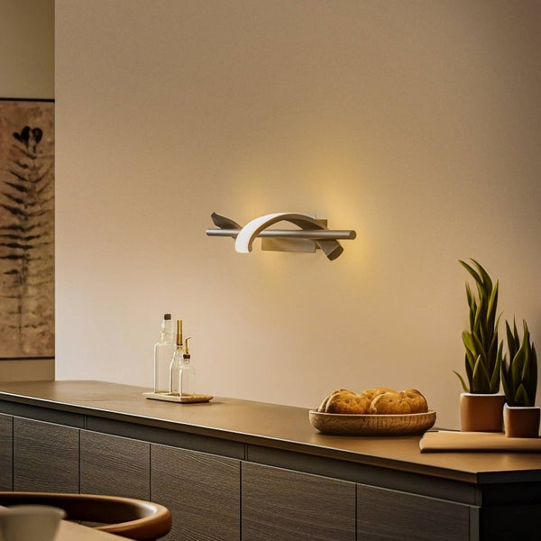 Moderne Wandleuchte mit geschwungenem Design über einem Sideboard in einer hellen Küche. Warmes Licht an einer neutralen Wand.
