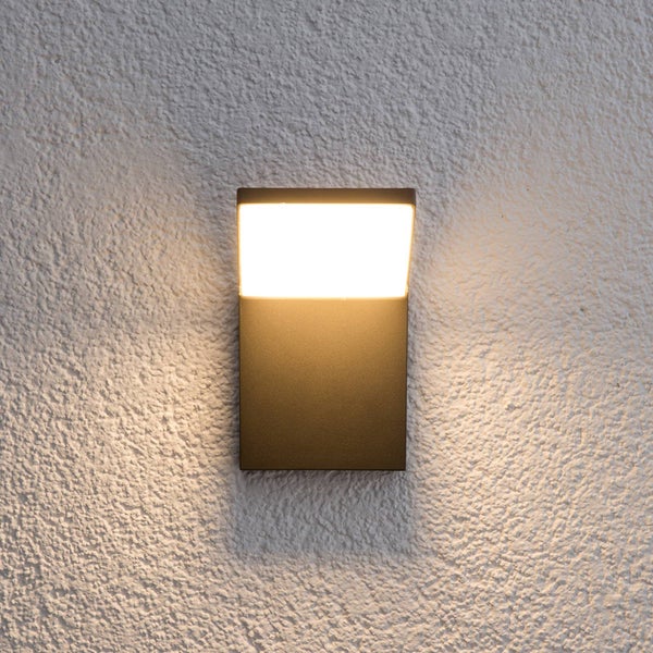 Moderne rechteckige LED Außenwandleuchte in Anthrazit mit warmweißem Licht montiert an einer verputzten Wand.