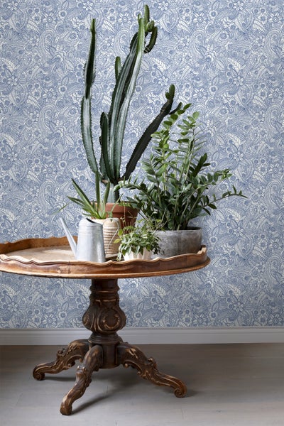 Dekoratives Interieur mit gemusterter Tapete, Pflanzen und rundem Tisch