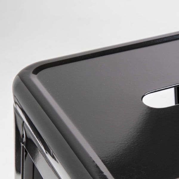 Detailaufnahme eines schwarzen Metallhockers mit glänzender Oberfläche und abgerundeter Ecke.