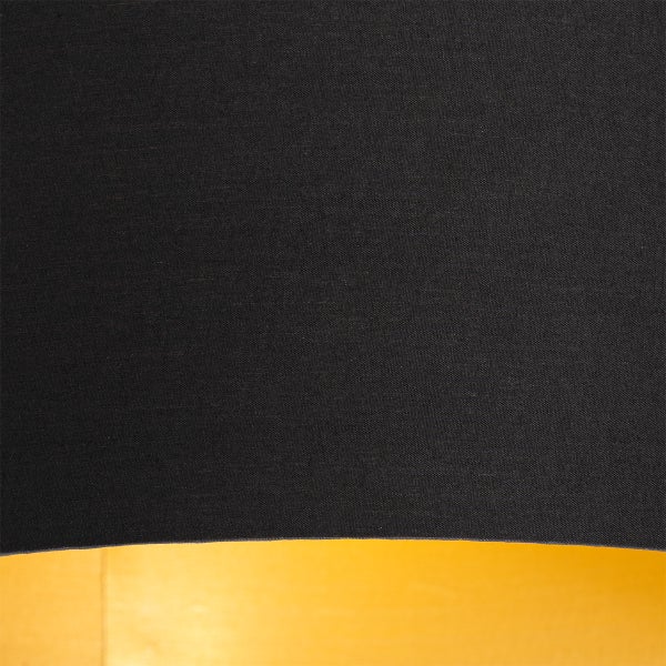 Nahaufnahme eines Lampenschirms aus schwarzem Textil mit goldfarbener Innenseite.