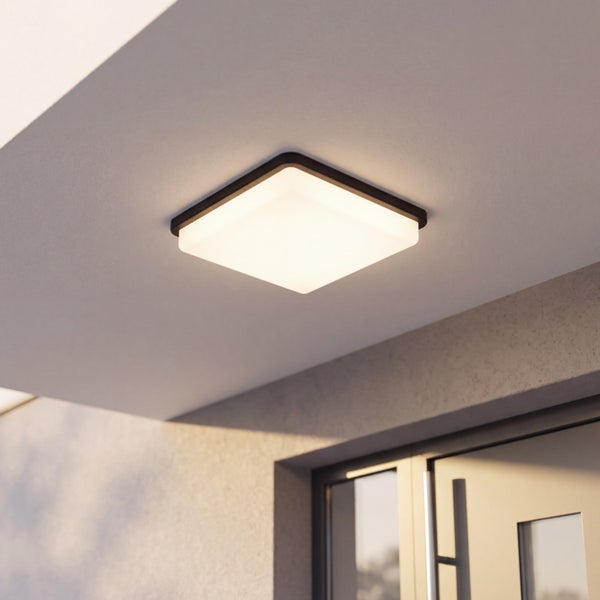 Quadratische LED-Deckenleuchte für den Außenbereich, eingeschaltet, montiert unter einem Vordach am Hauseingang.