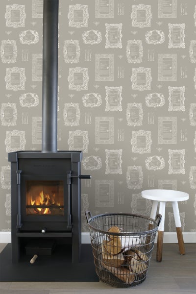 Kaminofen mit Brennholzkorb und Hocker vor einer gemusterten Tapete