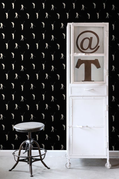 Raumansicht mit Tapete mit Golfmotiven, weißem Metallschrank und Hocker