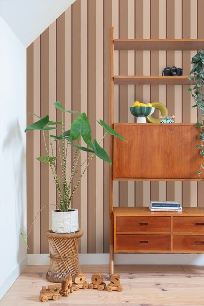 Raumansicht mit gestreifter Tapete, Holzregal, Zimmerpflanze und Holzspielzeug