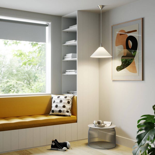 Heller Lesebereich mit gelber Sitzbank am Fenster, weißem Einbauregal, einer kegelförmigen Pendelleuchte und einem modernen Draht-Beistelltisch.