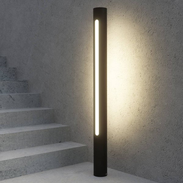 Moderne LED-Wegeleuchte in Säulenform vor einer Betonwand neben einer Treppe. Minimalistisches Design aus Metall.