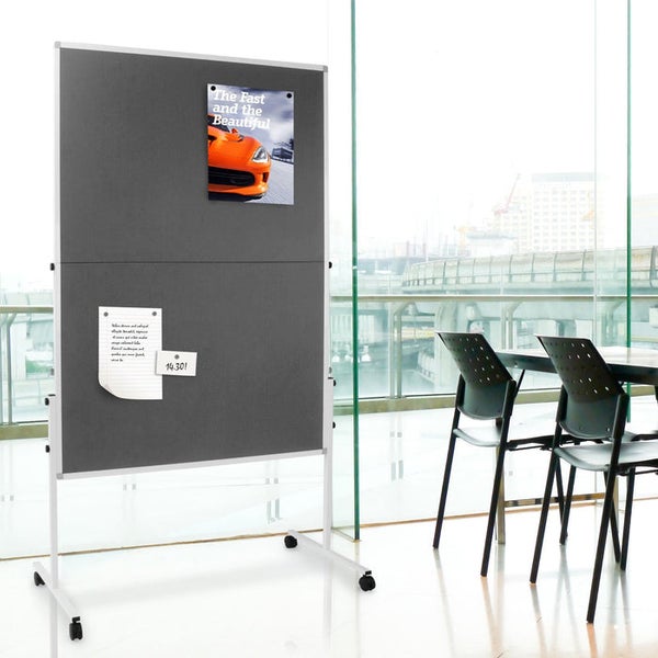 Fahrbare graue Filzpinnwand auf weißem Metallgestell mit Rollen, genutzt als Raumteiler in einem hellen, modernen Büro mit Glasfront.