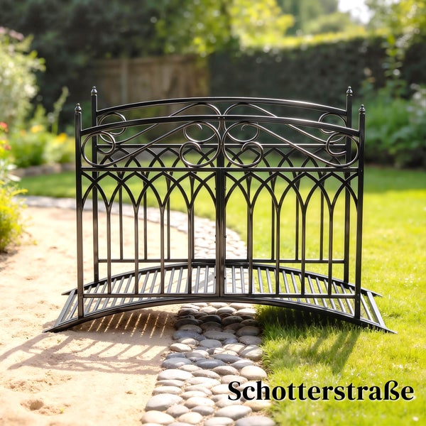 Dekorative Gartenbrücke aus Metall mit verzierten Geländern über einem Gartenweg.