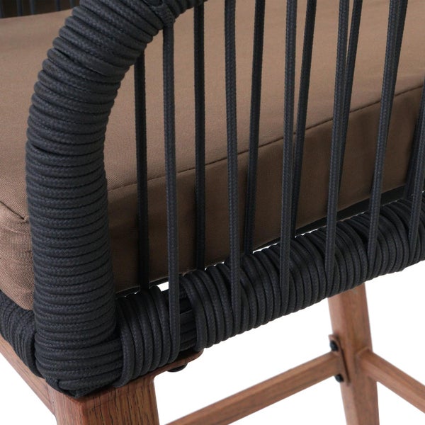 Detailansicht eines Barstuhls mit Sitzkissen, geflochtenem Rahmen und Holzbeinen