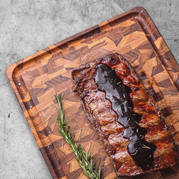 Spareribs mit Soße und Rosmarin auf einem Holzbrett