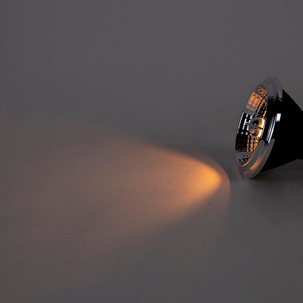 Eingeschaltetes LED-Leuchtmittel mit warmweißem Lichtkegel auf einer neutralen Oberfläche.