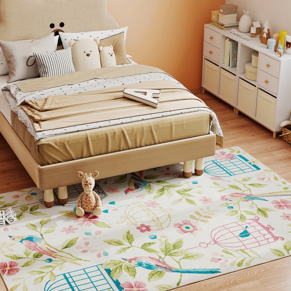 Kinderteppich mit Vögeln und Blumen in einem hellen Kinderzimmer mit Holzbett, Giraffen-Plüschtier und weißem Aufbewahrungsregal.