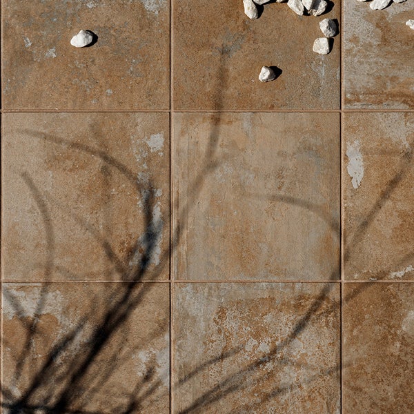 Quadratische Bodenfliesen mit natursteinartiger Oberflächenstruktur und verlegtem Fugenbild.