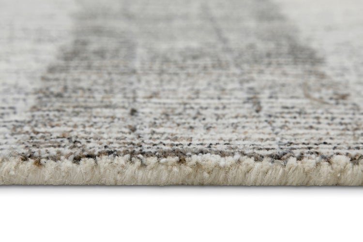 Detailaufnahme einer Teppichkante mit sichtbarer Florhöhe und strukturierter Oberfläche.