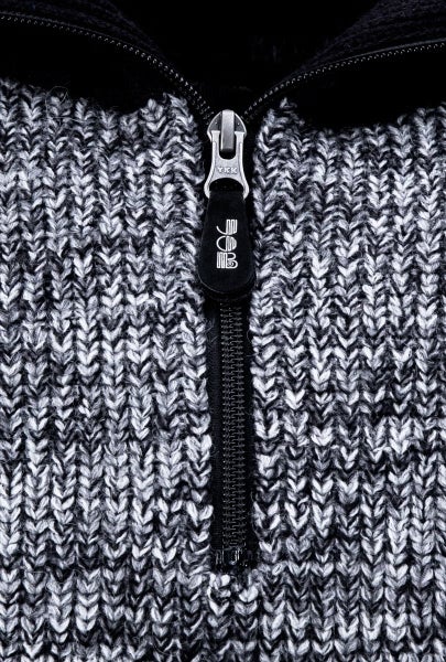 Nahaufnahme eines Reißverschlusses an einer Strickjacke mit FHB Logo.