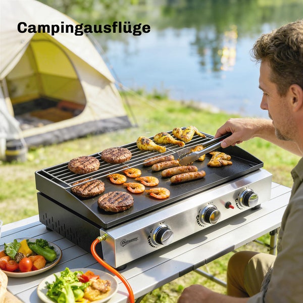 Mobiler Outsunny Gasgrill aus Edelstahl auf einem Campingtisch am See mit Grillgut, neben einem Zelt in heller Außenumgebung.