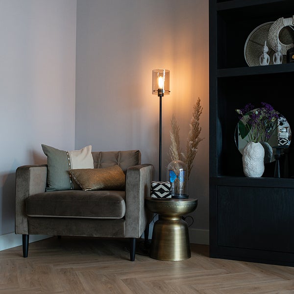 Einrichtungsbeispiel: Sessel mit Kissen, Stehlampe, Beistelltisch und Regal in einem Wohnraum