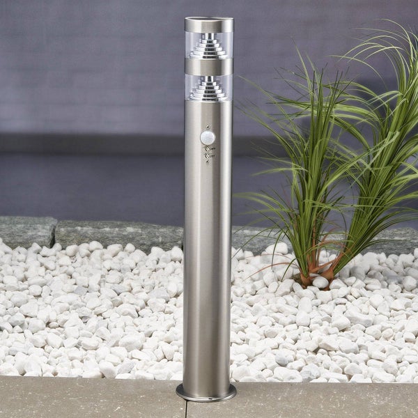 Außenstandleuchte aus Edelstahl mit Bewegungsmelder und zwei transparenten Lichtelementen in einem Gartenbeet mit weißen Steinen.