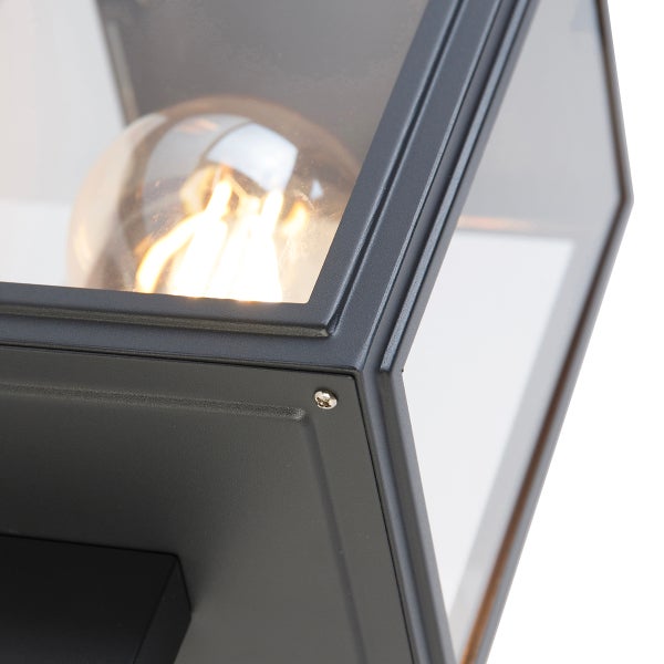 Nahaufnahme einer Außenwandleuchte aus Metall und Glas mit leuchtendem Leuchtmittel.