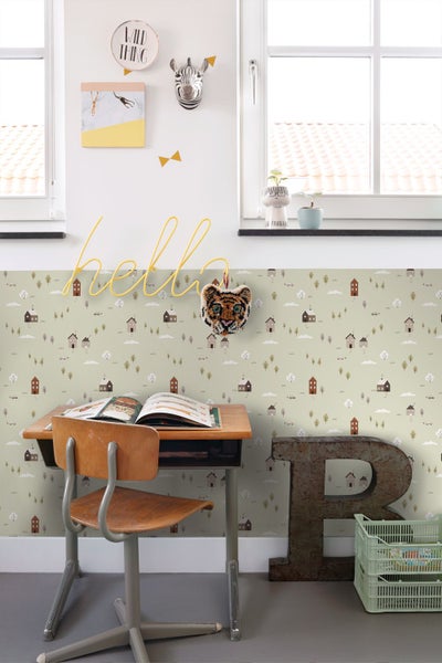 Kinderzimmer mit gemusterter Tapete mit Häusern und Bäumen, Schreibtisch aus Holz und Wanddekoration.