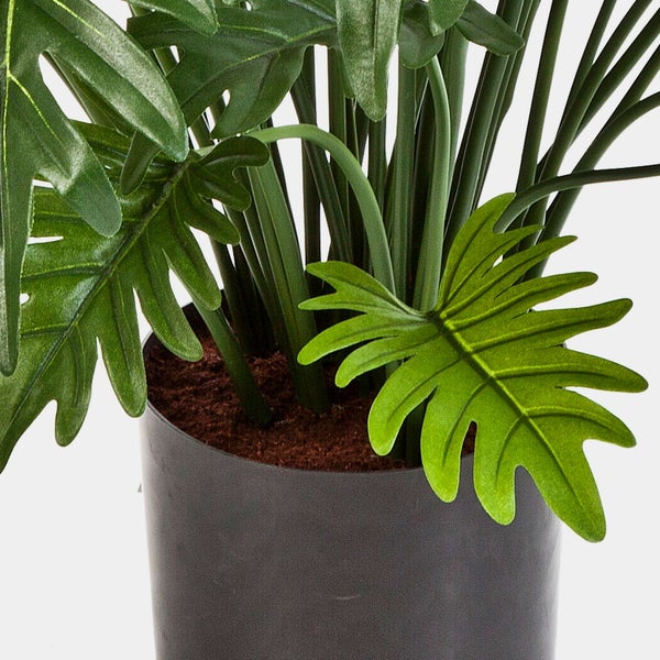 Nahaufnahme von grünen Blättern an einem künstlichen Pflanzenstiel aus Kunststoff.