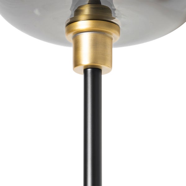 Detailansicht einer Leuchte mit schwarzem Metallstab, Verbindungselement aus Messing und Schirm aus Rauchglas.