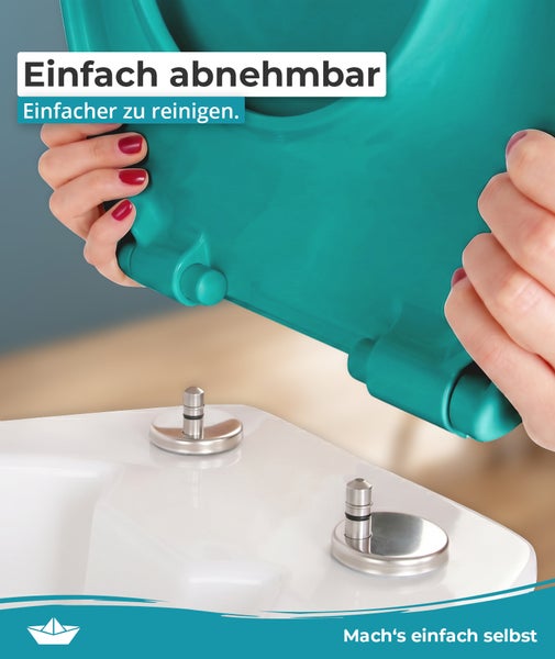 Ein abnehmbarer Toilettensitz wird von einer Hand auf die metallischen Befestigungselemente einer Toilette aufgesetzt