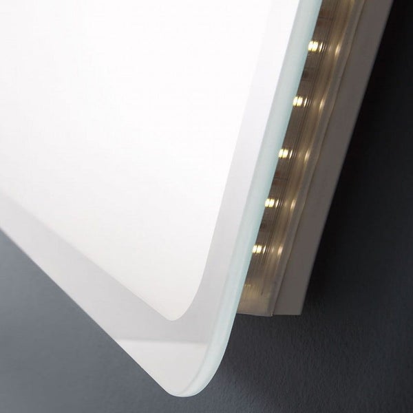 Detailansicht eines Badspiegels mit integrierter LED-Beleuchtung und abgerundeter Ecke.