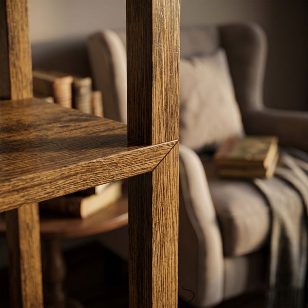 Detailaufnahme eines Holzregals mit rustikaler Maserung in einem Wohnzimmer vor einem Sessel mit Büchern.