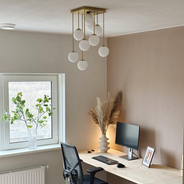 Szene eines Arbeitszimmers mit einer Hängeleuchte mit mehreren Kugeln, einem Schreibtisch und Büromaterialien.