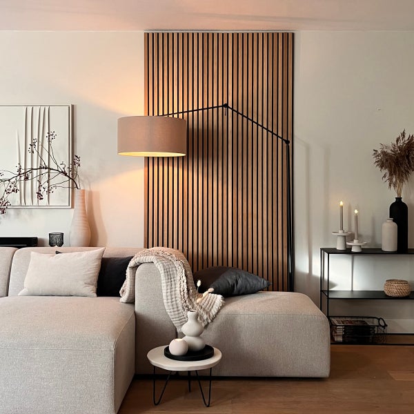 Wohnzimmer mit Couch, Stehlampe, Akustikpaneelen und dekorativen Elementen für eine gemütliche Atmosphäre