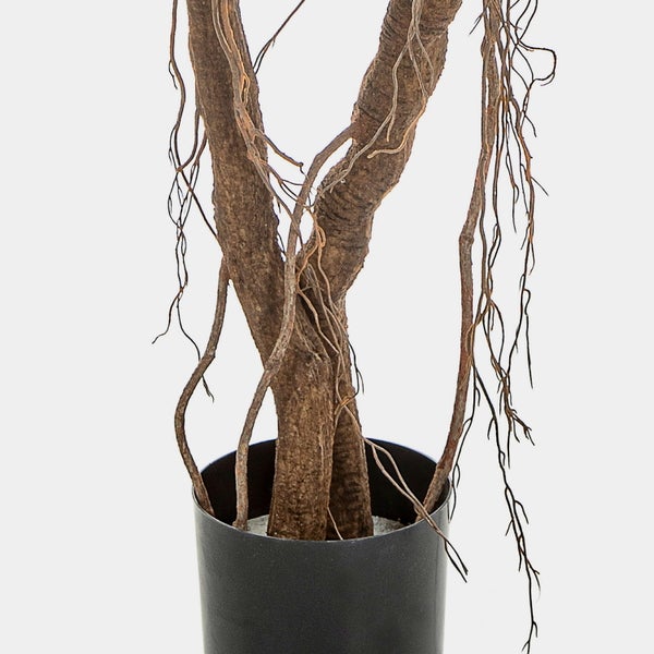 Künstliche Pflanze mit grünen dornigen Stielen in einem weißen Topf mit Ziersteinen.