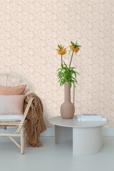 Wohnraum mit Tapete mit floralem Muster, Rattan-Stuhl und Beistelltisch mit Blumen in Vase